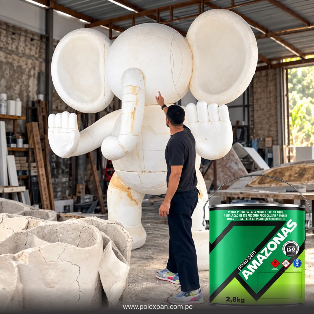 Taller donde un hombre da los últimos toques a una escultura gigante de tecnopor con forma de elefante, con bloques en bruto en primer plano; delante, la lata de 1 galón de pegamento Amazonas.
